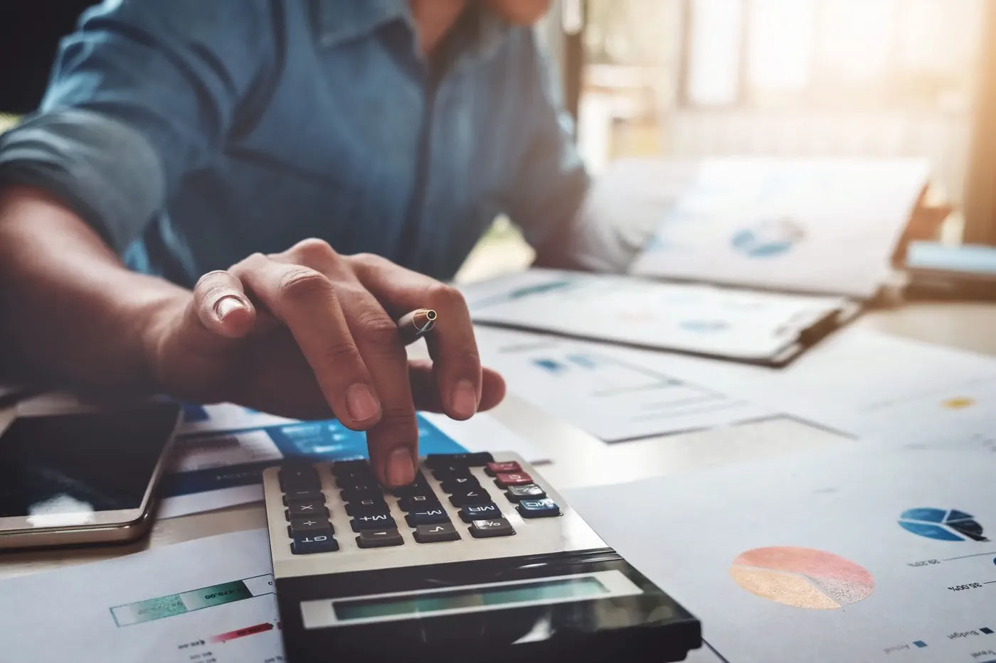 Business man using a calculator with a laptop, budget and loan papers in an office