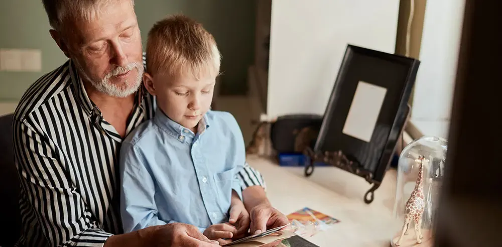 Grandfather and grandson looking at photos together at home