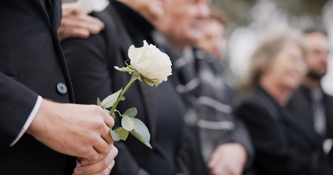 Mourner holding a rose at a graveside memorial service